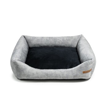 Graues Haustierbett mit einem plüschigen schwarzen Innenraum und einem Lederetikett an der Seite, entworfen für Komfort und Stil.