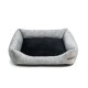 Graues Haustierbett mit einem plüschigen schwarzen Innenraum und einem Lederetikett an der Seite, entworfen für Komfort und Stil.
