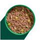 Eine grüne Schüssel gefüllt mit Haustierfutter, das eine strukturierte, fleischähnliche Mischung mit kleinen gewürfelten Apfelstücken oben hat.