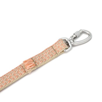 Nahaufnahme einer gewebten Haustierleine in sanften Pfirsich- und Cremetönen, mit einem stabilen silbernen Metallclip zur Befestigung.