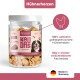 Eine Hand hält ein Hundeleckerli mit der Aufschrift "100% Hühnerherzen", "0g", "Ohne Zucker oder Zusatzstoffe", "Ideal für Training & Belohnung."