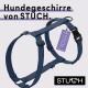 Marineblaue Hundegeschirr von STUCH mit einem "PETA Approved Vegan"-Etikett, auf einem hellgrauen Hintergrund präsentiert.