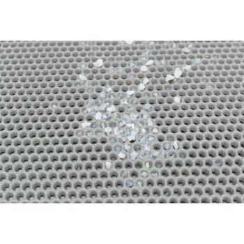 Nahaufnahme einer strukturierten grauen Oberfläche mit kleinen weißen und blauen Fragmenten, die darauf verstreut sind und einem Material für Haustierprodukte ähneln.