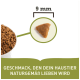 Nahaufnahme von 9 mm dreieckigen Haustierfutter-Kibble in einer Schüssel mit dem Text: "GESCHMACK, DEN DEIN HAUSTIER NATURGE MÄß LIEBEN WIRD."