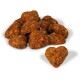 A pile of heart-shaped pet treats in a reddish-brown color, with visible bits of seeds and vegetables, on a white background.