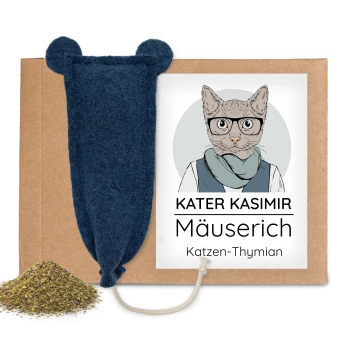 Blaues Filz-Mäusespielzeug mit Seilschwanz auf Karton, Haufen von Kräutern, Etikett zeigt Katze und Text 'KATER KASIMIR Mäuserich'.