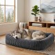 Sibirischer Husky zusammengerollt schlafend in einem weichen, grauen Cordstoff-rechteckigen Hundebett in einem gemütlichen Wohnzimmer mit Fenster und Pflanze.