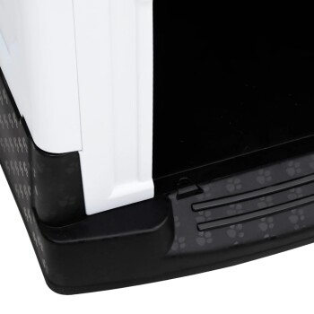 Eine Nahaufnahme einer Haustiertrage mit einem weißen Oberteil und einem schwarzen Boden mit einem Pfotenabdruckmuster, die den Eingang und das Innere zeigt.