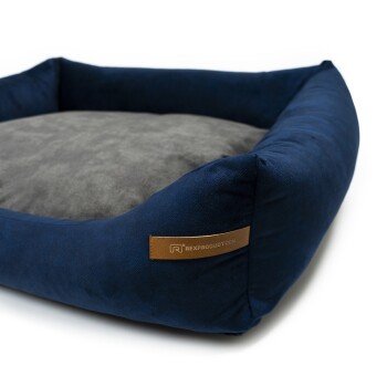Marineblaues Haustierbett mit einem weichen grauen Kissen, das ein Lederetikett mit der Aufschrift 'RexProduct.com' trägt.