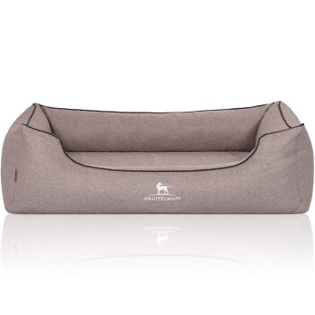 Ein gemütliches, graues Hundebett mit niedriger Rückenlehne und erhöhten Seiten, mit dem Logo "KNUFFELWUFF" auf der Vorderseite gestickt.