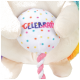 Un jouet en peluche coloré avec une balle ronde à pois qui dit "CÉLÉBRER" en lettres grasses, tenue par des pattes douces et beiges.