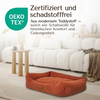 Hundebett aus orangefarbenem Teddy-Stoff, mit der Aufschrift "Zertifiziert und schadstofffrei", auf einem gemütlichen Wohnzimmerteppich mit einem Couchtisch und Sofa.