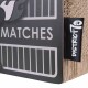Eine Nahaufnahme einer Haustierproduktverpackung mit der Aufschrift "MATCHES" auf schwarzem Hintergrund und einer strukturierten beigen Seite, mit einem "DISTRICT 7"-Tag.