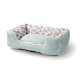 Un lit pour animaux confortable avec un extérieur doux de couleur vert menthe et un intérieur à motif géométrique en couleurs pastel.