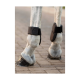Nahaufnahme der Beine eines Pferdes, das schwarze schützende Hufschuhe trägt, auf einem Kopfsteinpflasterweg stehend.