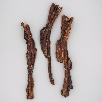 Drei Stücke getrocknete Fleischstreifen für Hunde, die eine zähe Textur und eine reichhaltige braune Farbe zeigen, auf einem hellgrauen Hintergrund.