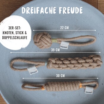 Drei Hundespielzeuge auf einem grauen Teller präsentiert: ein Knoten (22 cm), ein Stock (39 cm) und eine doppelte Schlaufe (30 cm), beschriftet mit "DREIFACHE FREUDE."