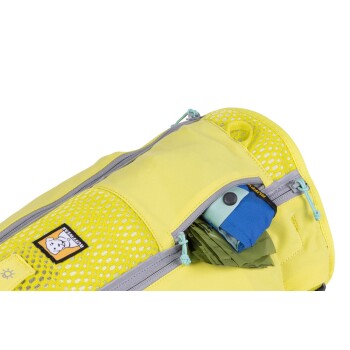 Eine Nahaufnahme eines leuchtend gelben Haustier-Rucksacks mit einer Netztasche, in der ein blauer und grüner Gegenstand teilweise sichtbar ist.