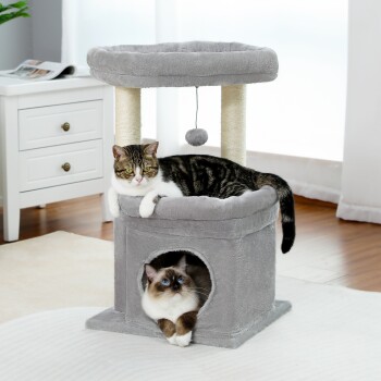 Eine verspielte Katze klettert auf einen natürlichen Sisalpfosten auf einem grauen Katzenbaum, der einen gemütlichen Rückzugsort und ein hängendes Spielzeug bietet, das die Pfotenreinigung fördert.