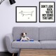 Ein kleiner Hund liegt auf einem grauen Sofa mit einer blauen Matte, umgeben von gerahmten Kunstwerken mit einer einfachen Hundeskizze und einem motivierenden Zitat.