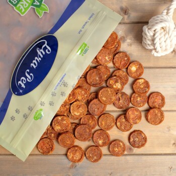 Eine Tüte mit Hundeleckerlis, beschriftet mit "Fruita Snack", mit einem transparenten Deckel, umgeben von runden, braunen Leckerlis auf einer Holzoberfläche.