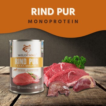 Wildfang 'RIND PUR' Monoprotein-Hundefutterdose neben rohen Rindfleischstücken und Petersilie auf Holz; sichtbar 'RIND PUR MONOPROTEIN'.