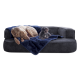 Ein großer Hund und ein kleiner Hund ruhen sich auf einer dunkelgrauen Couch aus, die mit einer weichen marineblauen Decke bedeckt ist.