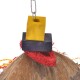 Buntes Vogelspielzeug mit einem gelben und lila Holzblock, rotem Sisal-Seil und einer Kokosnussschalenbasis, die an einer Metallkette hängt.