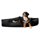 Ein Berner Sennenhund, der bequem auf einem schwarzen Haustierbett liegt und entspannt mit herausgestreckter Zunge aussieht.