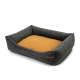 Graues Haustierbett mit einem weichen orangefarbenen Kissen, mit erhöhten Seiten für Komfort und einem kleinen Lederschild an der Seite.