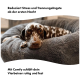 Ein gefleckter Hund, der bequem auf einem plüschigen grauen Hundebett ruht, mit Text, der angibt, dass es Stress und Trennungsangst von der ersten Nacht an reduziert.