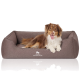 Ein braunes Hundebett mit einem plüschigen Design, auf dem ein Hund bequem liegt. Das Bett hat das Logo 'KNUFFELWUFFF' deutlich sichtbar.