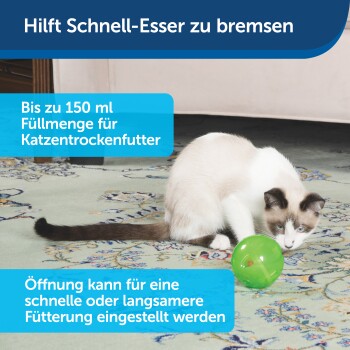 Eine Siamkatze spielt mit einem grünen Futterball auf einem gemusterten Teppich. Der Text lautet: "Hilft Schnell-Esser zu bremsen." Kapazität: 150 ml.