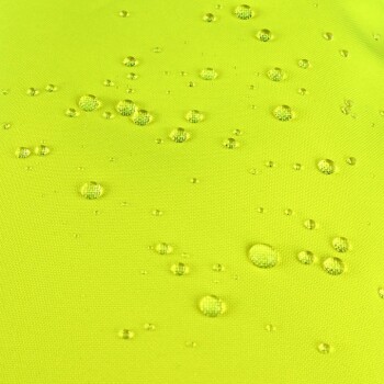 Nahaufnahme eines leuchtend gelben Stoffes mit Wassertropfen, die über die Oberfläche verteilt sind, und zeigt ein wasserdichtes Material.