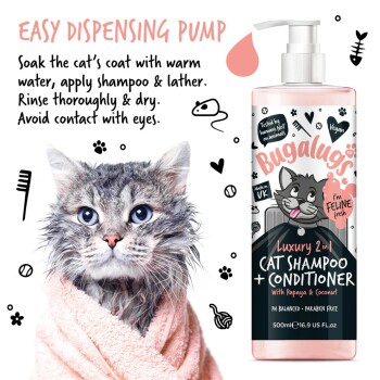 Eine nasse Katze, die in ein pinkes Handtuch gewickelt ist, schaut in die Kamera, neben einer Flasche Bugalugs Luxury 2-in-1 Katzen-Shampoo + Conditioner.