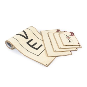 Eine gerollte Tiermatte mit dem Wort "FEED" in großen schwarzen Buchstaben, neben drei kleineren Matten mit dem Wort "LOVE" und dekorativen Designs.