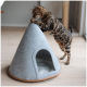 Eine verspielte Bengal-Katze interagiert mit einem grauen Filz-Haustierzelt, das einen vorderen Eingang hat, auf einem hellen Holzboden.