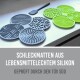 Eine Nahaufnahme eines Hundes, der eine grüne Silikon-Futtermatte mit vier verschiedenen Texturen leckt, beschriftet mit "4 verschiedene Strukturen."