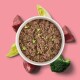 Schüssel mit Haustierfutter mit gemischten Zutaten, umgeben von Lachs-, Zucchini- und Kürbisscheiben, auf einem hellblauen Hintergrund.