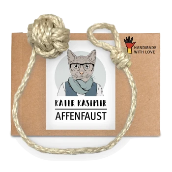 Ein braunes Kartonpaket, das mit einem Seil gebunden ist, mit einem Etikett, das "KATER KASIMIR AFFENFAUST" liest und einer Grafik einer Katze.