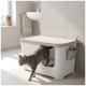 Grijze gestreepte kat die een moderne witte afgesloten kattenbak met schephouder verlaat in een lichte badkamer.