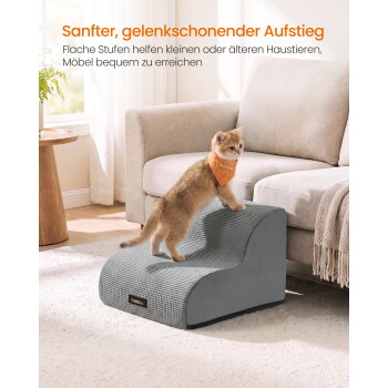 Kätzchen mit orangefarbener Bandana auf grauen Haustiertreppen neben dem Sofa; sichtbarer Text 'Sanfter, gelenkschonender Aufstieg'.