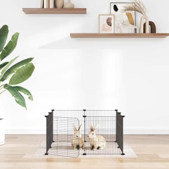 Schwarzes Metall-Haustierlaufgehege mit zwei Kaninchen darin, auf einem Teppich in einem hellen Raum mit Pflanzen und Wandkunst platziert.