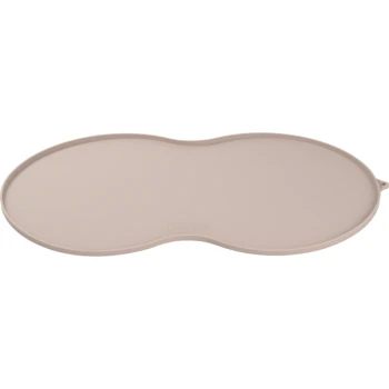 Un tapis de nourriture pour animaux de compagnie beige en forme ovale avec des bords surélevés, conçu pour attraper les déversements et garder les zones de nourriture propres.