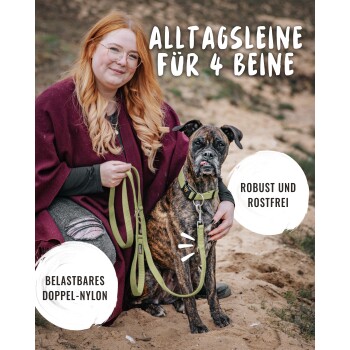 Eine Frau in einem kastanienbraunen Poncho hält eine grüne Leine für einen gestromten Hund. Text: 'ALLTAGSLEINE FÜR 4 BEINE', 'ROBUST UND ROSTFREI.'