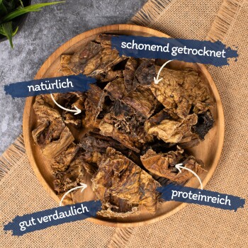 Getrocknete Haustierleckerlis auf einem Holzbrett mit Etiketten: 'natürlich', 'sanft getrocknet', 'leicht verdaulich' und 'reich an Protein'.