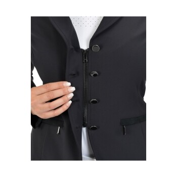 Nahaufnahme einer Hand, die den Reißverschluss einer schwarzen Jacke hält, die mit Knöpfen und Taschen ausgestattet ist, darunter ein weißes gepunktetes Hemd.