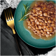 Une assiette teal remplie de nourriture pour animaux humide et hachée dans une sauce, garnie d'une branche de romarin, à côté d'une fourchette dorée sur une serviette noire.