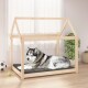 Ein gemütliches Holz-Hundebett in Form eines Hauses mit einem grauen Kissen und einem entspannten sibirischen Husky, umgeben von einem Fußball und einem Tennisball.