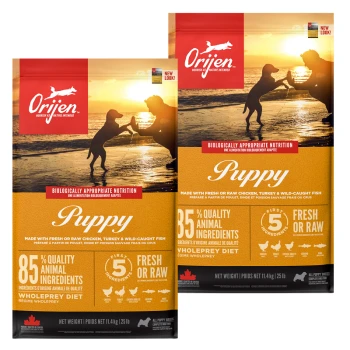Two bags of Orijen Puppy dog food with a sunset backdrop, showcasing "85% Quality Animal Ingredients" and "Biologically Appropriate Nutrition."